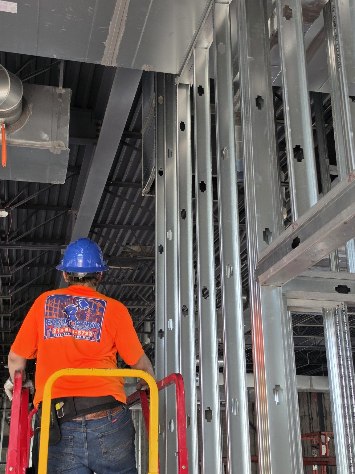 Right Hand Construction team member in a hard hat working on interior framing