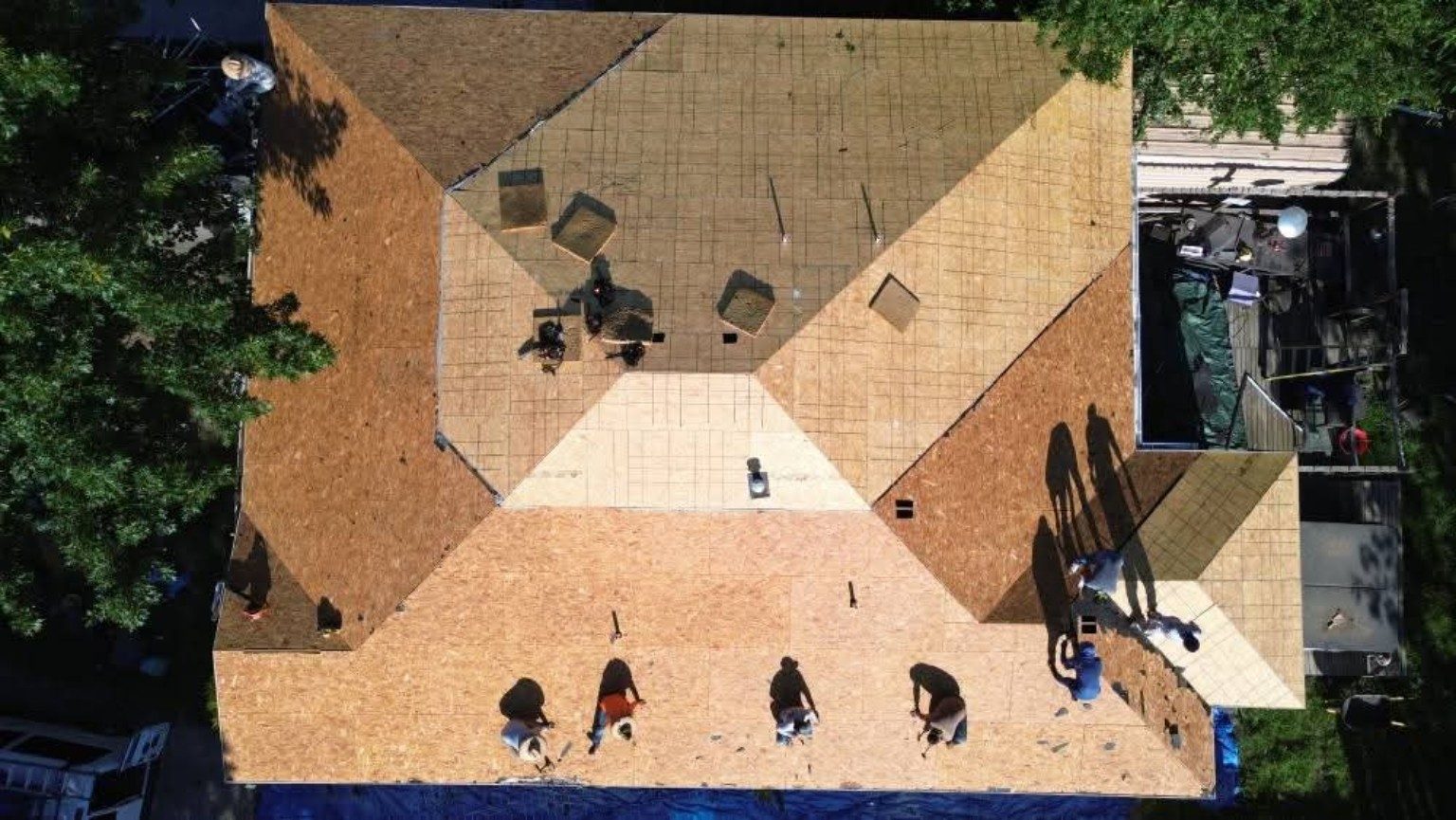 Aerial view of a roofing crew working across a residential roof