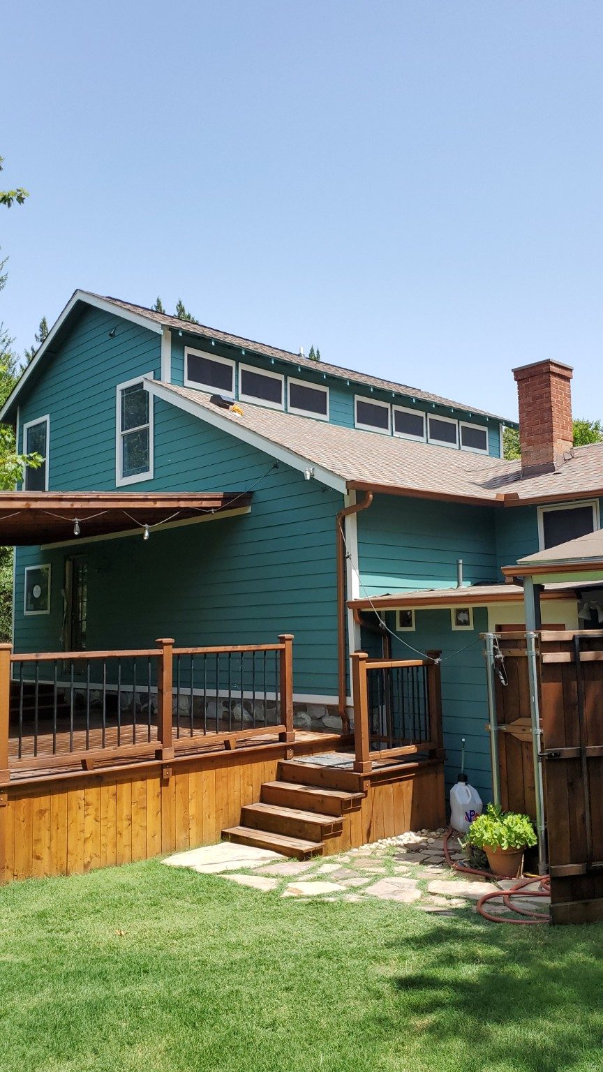Exterior of a teal home with a new cedar deck, stairs, and railing