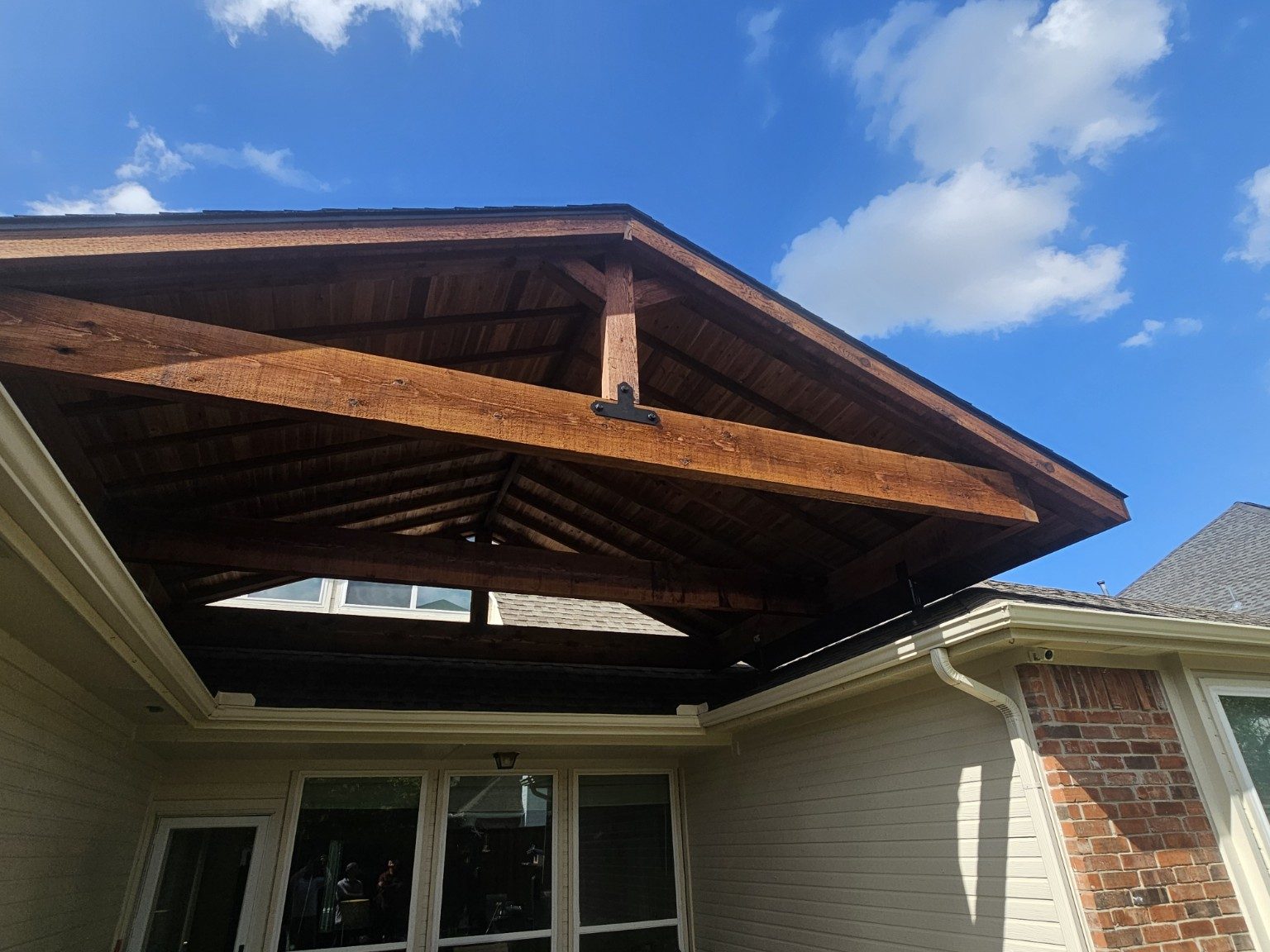 Finished covered patio with stained timber framing and a vaulted tongue-and-groove ceiling