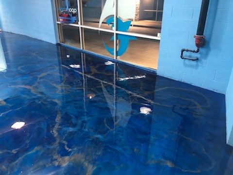 Deep blue metallic epoxy floor with a mirror-gloss finish in a commercial space