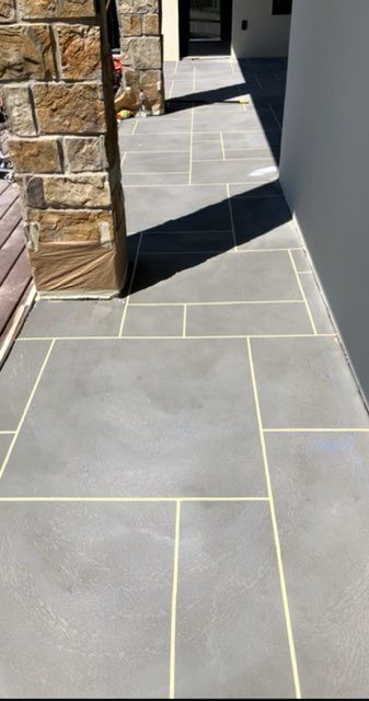 Decorative scored and stained concrete walkway alongside a stone exterior wall