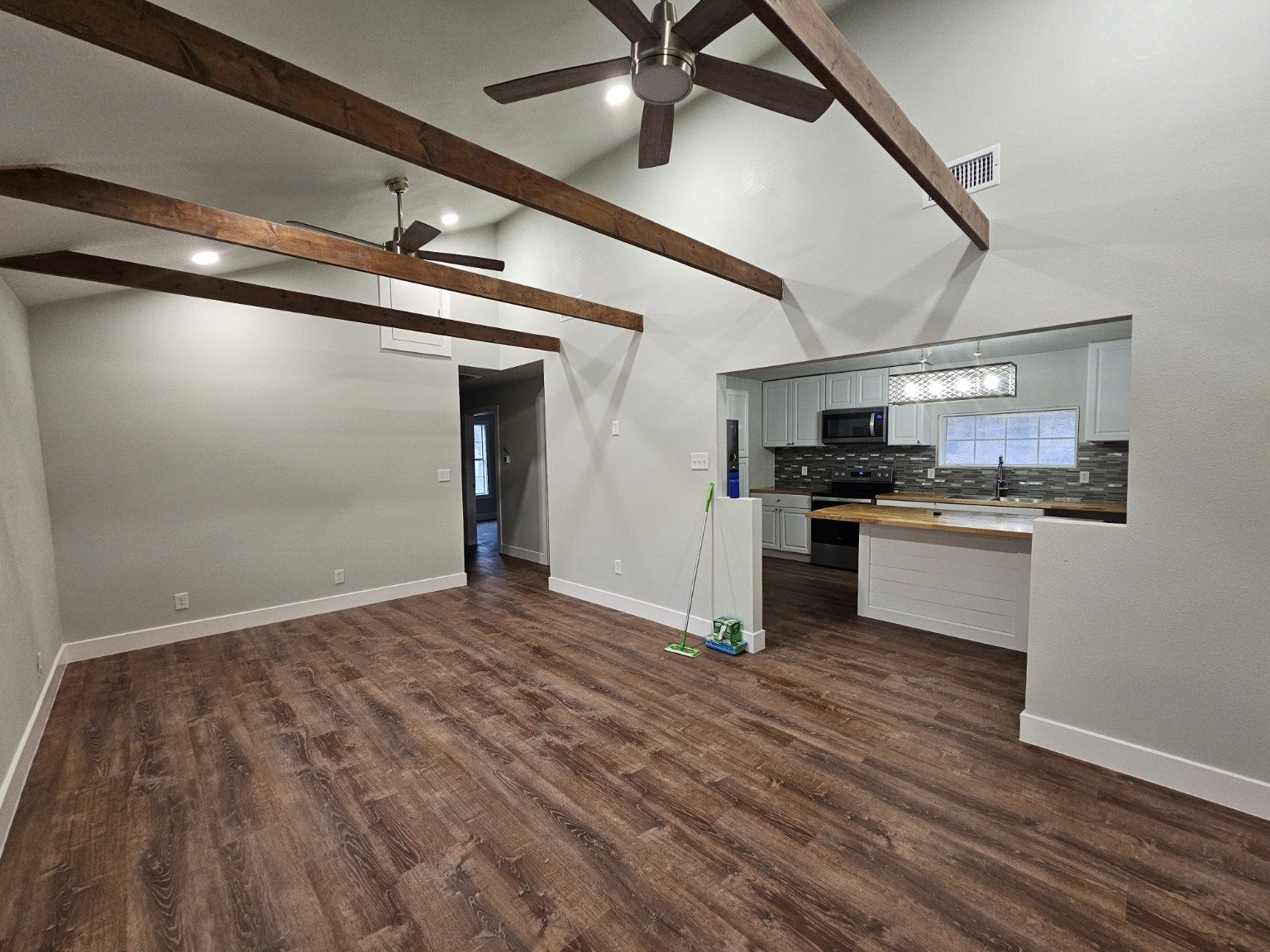 Remodeled open living area with exposed wood beams and new flooring