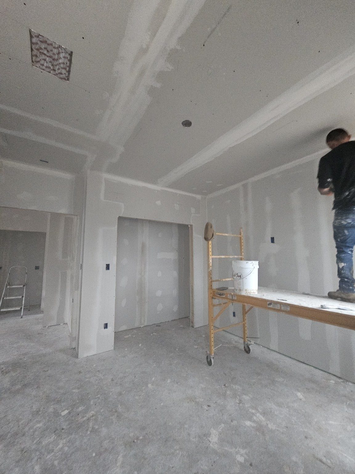Crew member finishing drywall in a newly framed room
