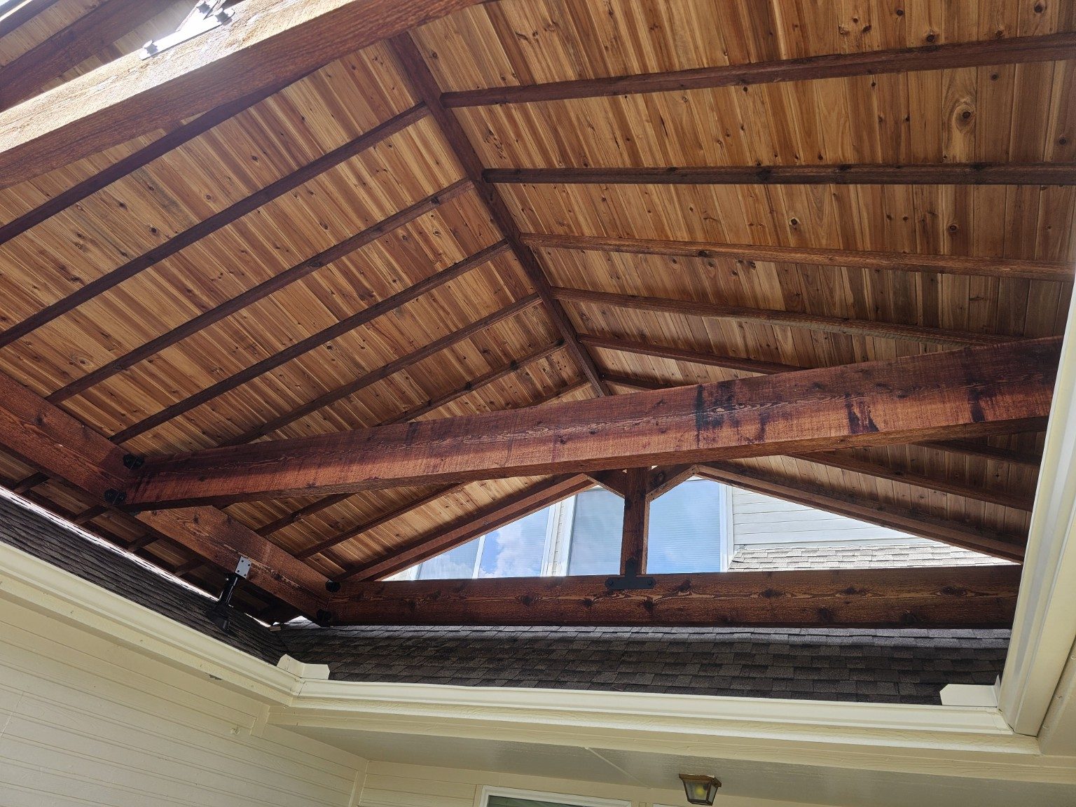 Stained timber patio roof structure with tongue-and-groove decking